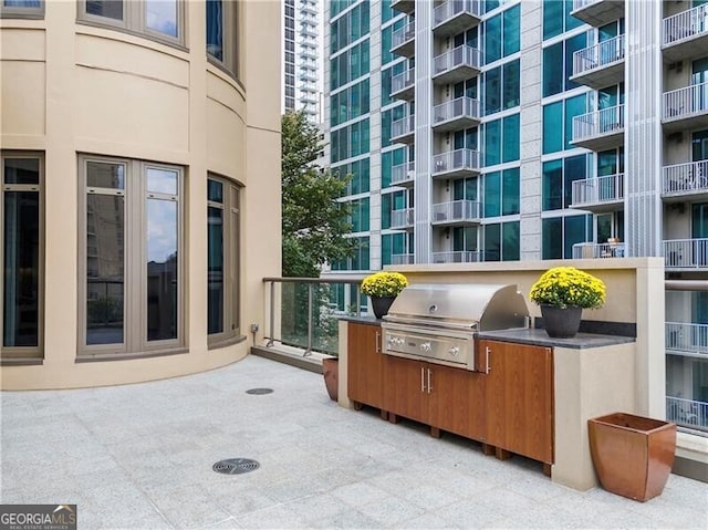 view of patio featuring a balcony, grilling area, and exterior kitchen