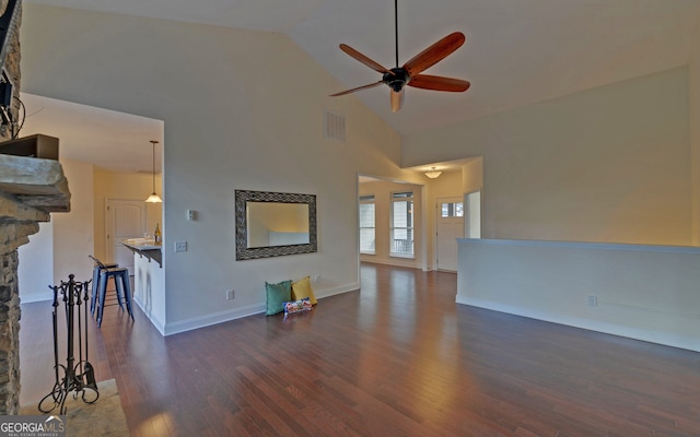 unfurnished living room with a stone fireplace, ceiling fan, high vaulted ceiling, and dark wood-type flooring