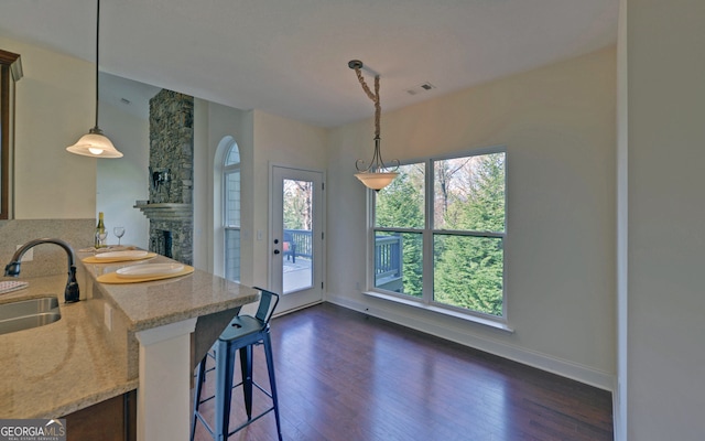 kitchen with a kitchen breakfast bar, sink, dark wood-type flooring, and decorative light fixtures