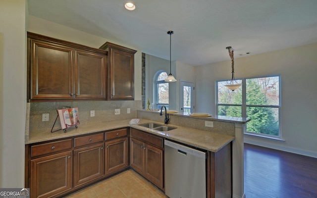 kitchen with sink, light hardwood / wood-style flooring, stainless steel dishwasher, kitchen peninsula, and decorative light fixtures