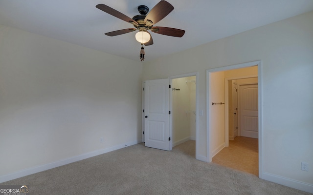 unfurnished bedroom with ceiling fan, light colored carpet, a spacious closet, and a closet