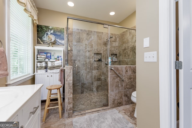 bathroom featuring a shower with shower door, vanity, and toilet