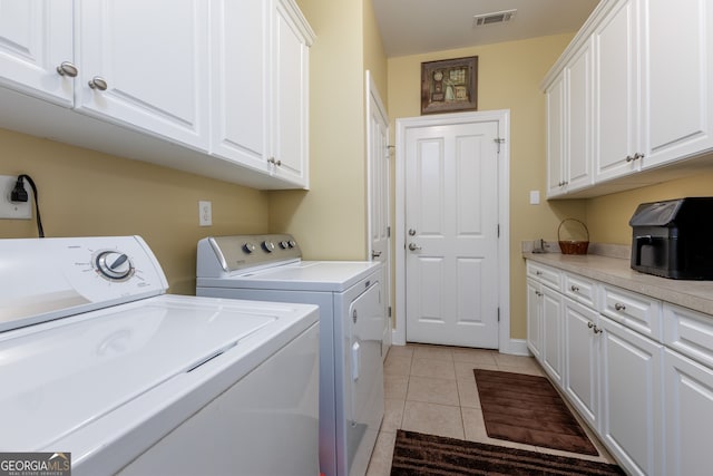 laundry room featuring light tile patterned flooring, cabinets, and separate washer and dryer