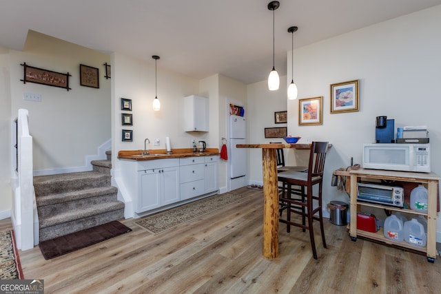 kitchen featuring pendant lighting, wooden counters, white appliances, and white cabinets