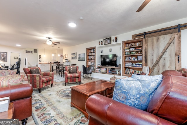 living room with ceiling fan and a barn door