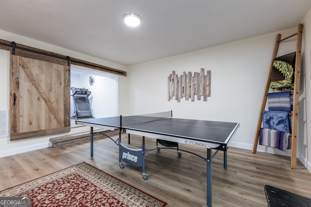 recreation room featuring a barn door and wood-type flooring