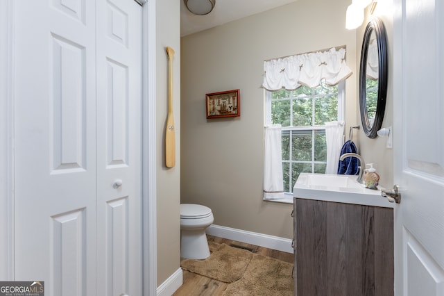 bathroom with toilet, vanity, and wood-type flooring