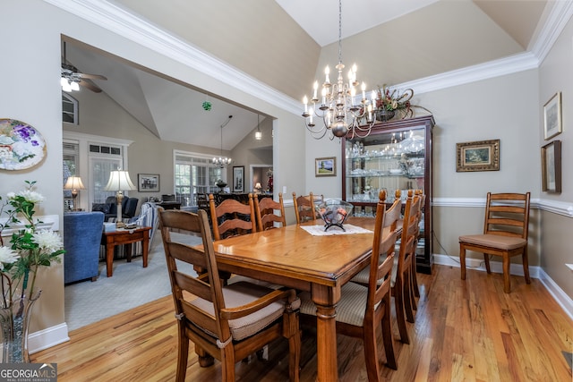 dining room with ceiling fan with notable chandelier, light wood-type flooring, crown molding, and vaulted ceiling