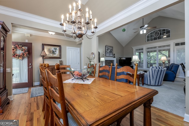 dining room with ceiling fan with notable chandelier, crown molding, hardwood / wood-style floors, and high vaulted ceiling