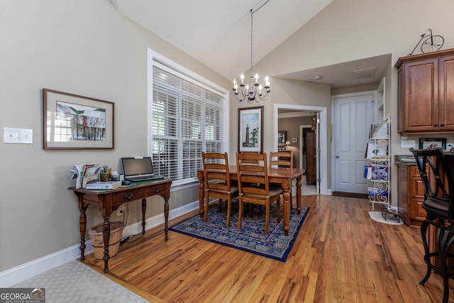 dining area with high vaulted ceiling, hardwood / wood-style floors, and an inviting chandelier