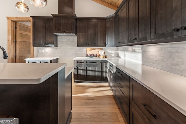 kitchen featuring tasteful backsplash, dark brown cabinets, hanging light fixtures, light hardwood / wood-style floors, and lofted ceiling