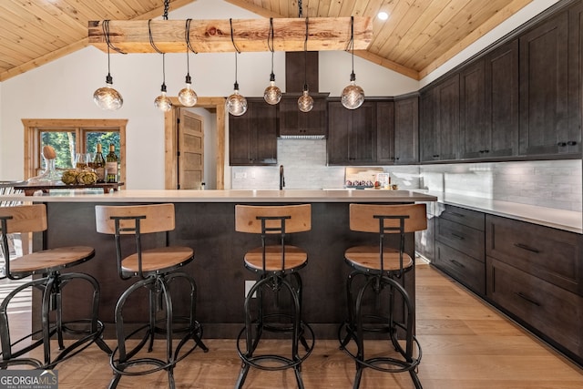 kitchen featuring light wood-type flooring, a kitchen island, hanging light fixtures, wooden ceiling, and lofted ceiling