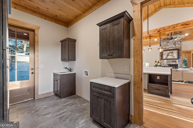 kitchen with a stone fireplace, lofted ceiling, dark brown cabinets, and wooden ceiling