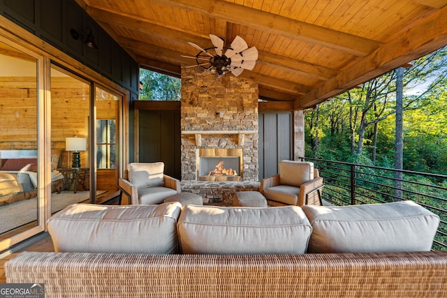 sunroom / solarium with vaulted ceiling with beams, wood ceiling, and an outdoor stone fireplace