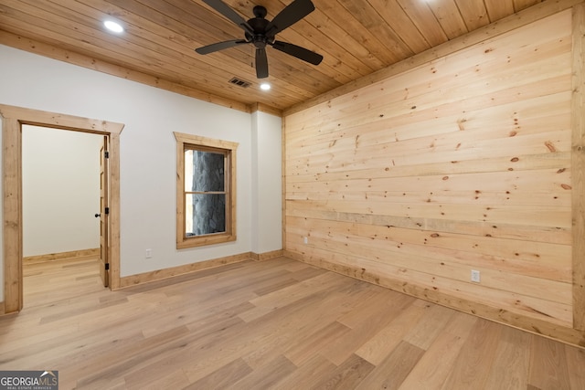 spare room featuring wood walls, wood ceiling, light hardwood / wood-style floors, and ceiling fan