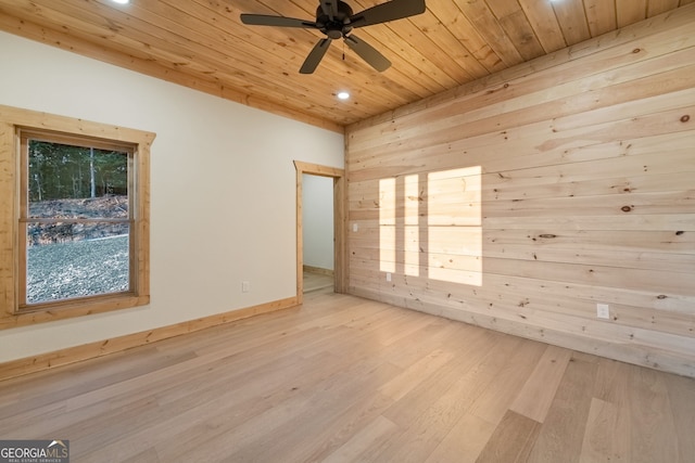 empty room with ceiling fan, wooden ceiling, light wood-type flooring, and wooden walls