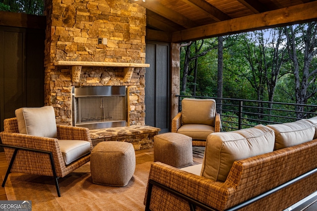 sunroom with vaulted ceiling with beams, wood ceiling, and an outdoor stone fireplace