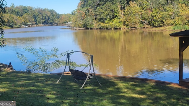 view of dock with a yard and a water view