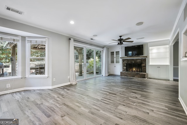 unfurnished living room featuring ornamental molding, a brick fireplace, hardwood / wood-style flooring, and ceiling fan