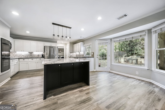 kitchen with a kitchen island, light hardwood / wood-style flooring, pendant lighting, white cabinets, and stainless steel refrigerator