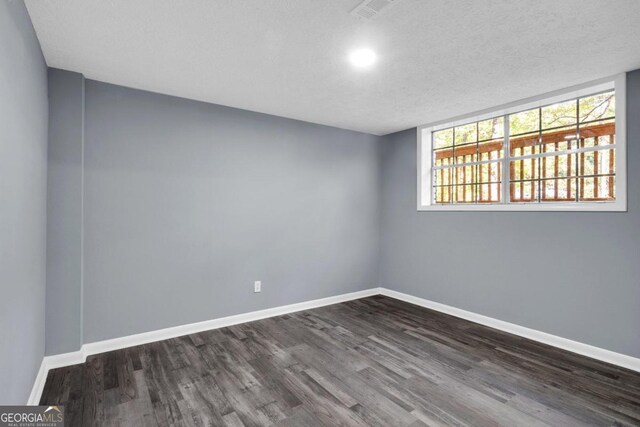 spare room with a textured ceiling and dark hardwood / wood-style floors