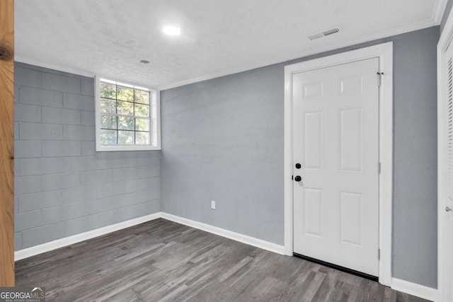 empty room with crown molding, a textured ceiling, and dark hardwood / wood-style floors