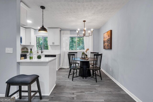 kitchen with a kitchen bar, a textured ceiling, kitchen peninsula, white cabinets, and dark wood-type flooring