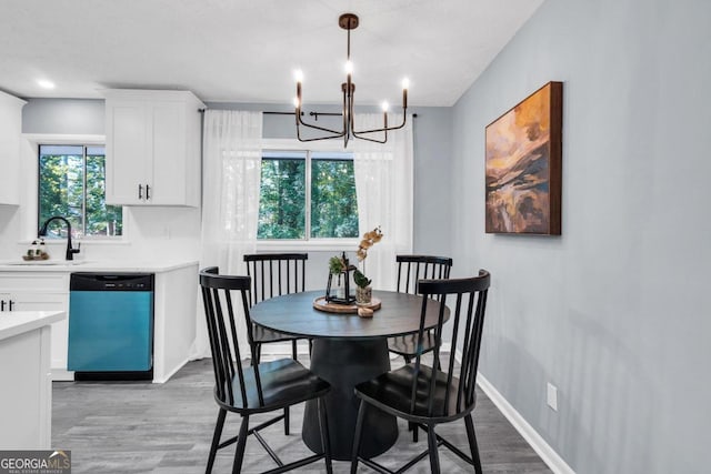 dining area with a notable chandelier, sink, and light wood-type flooring