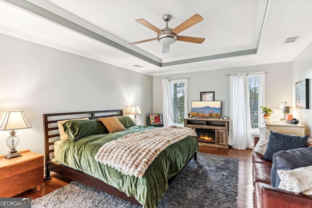 bedroom featuring dark hardwood / wood-style flooring, crown molding, a raised ceiling, and ceiling fan