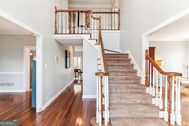 stairway with hardwood / wood-style floors and crown molding