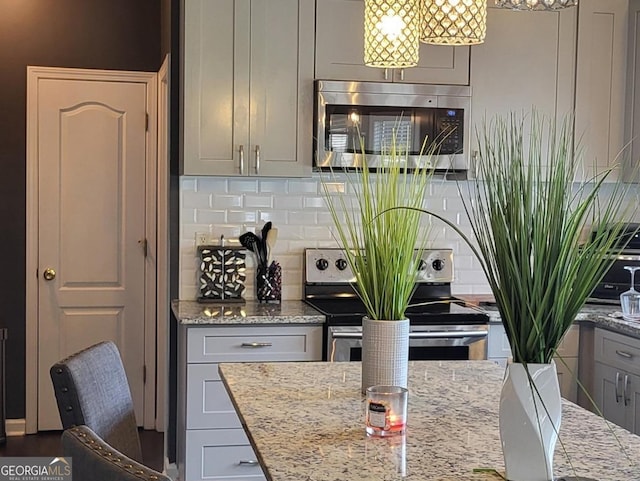 kitchen featuring light stone countertops, backsplash, stainless steel appliances, and gray cabinets