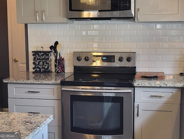 kitchen featuring decorative backsplash, light stone counters, and appliances with stainless steel finishes