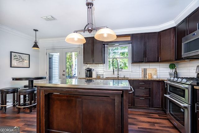 kitchen featuring dark brown cabinetry, pendant lighting, sink, dark wood-type flooring, and stainless steel appliances