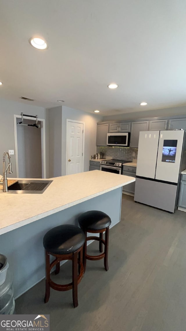 kitchen featuring gray cabinetry, light hardwood / wood-style floors, a breakfast bar area, and appliances with stainless steel finishes