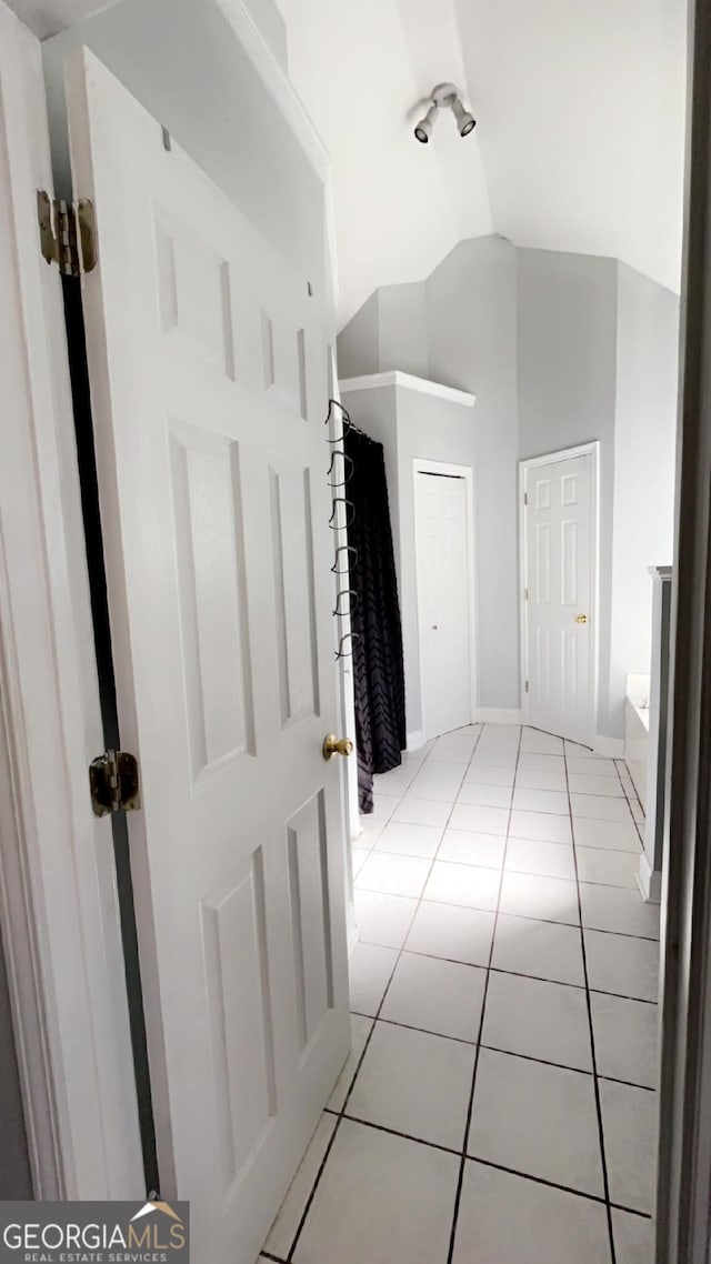 hall featuring light tile patterned flooring and lofted ceiling