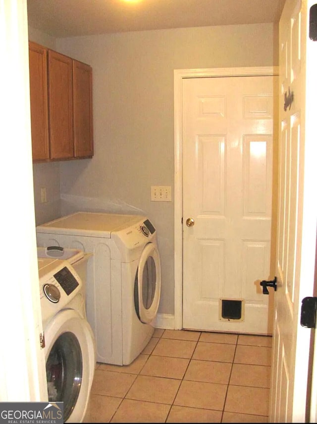 clothes washing area featuring washer and clothes dryer, light tile patterned floors, and cabinets