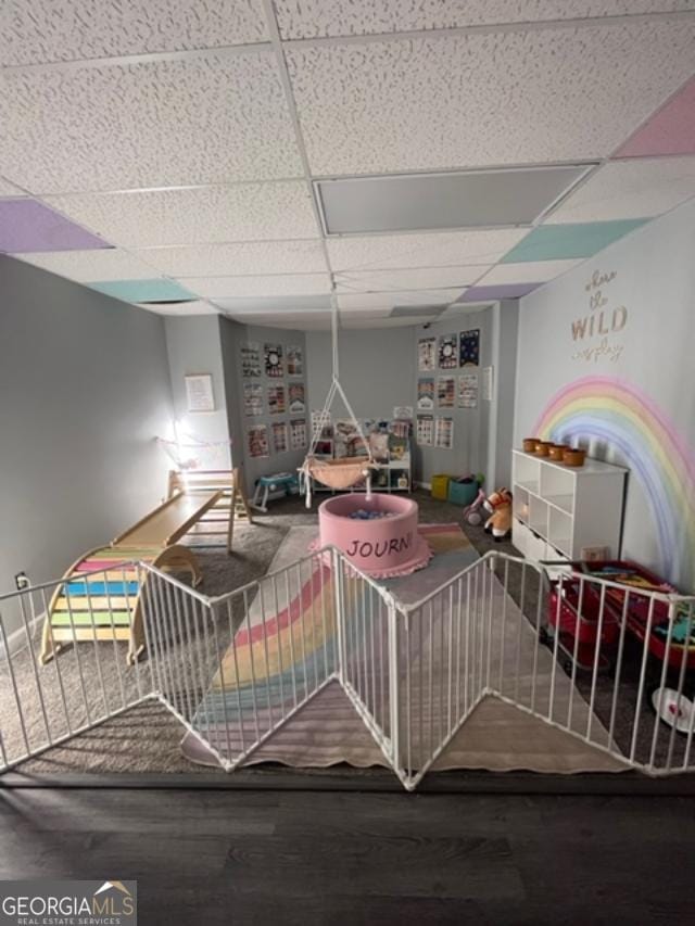 playroom featuring wood-type flooring and a paneled ceiling