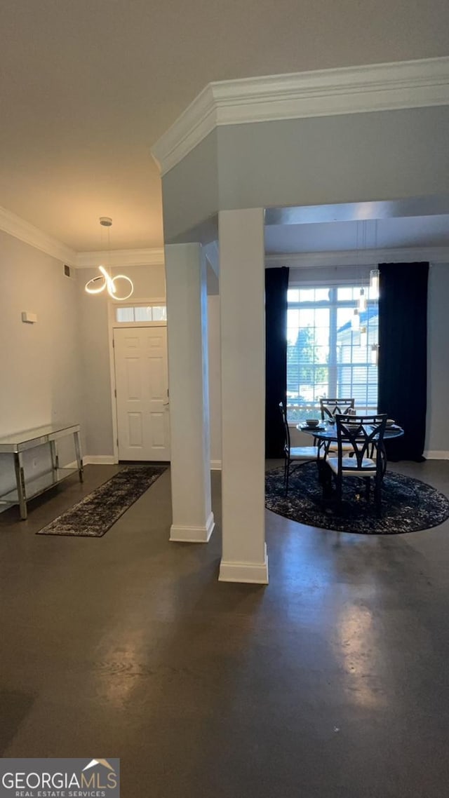 foyer entrance with concrete flooring, a chandelier, and ornamental molding