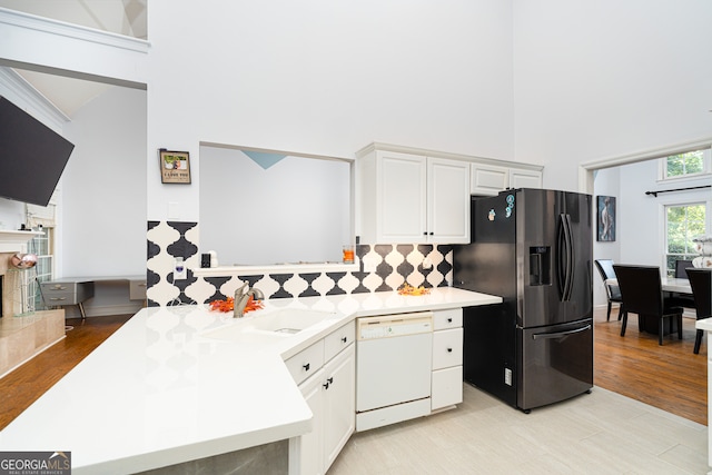 kitchen with sink, stainless steel fridge with ice dispenser, white cabinetry, dishwasher, and a high ceiling