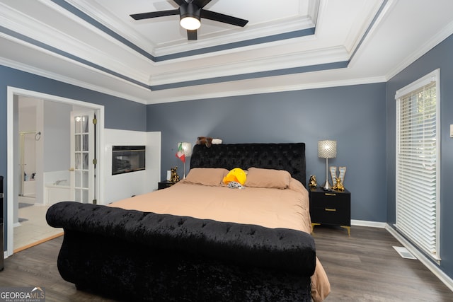 bedroom with ceiling fan, a raised ceiling, dark hardwood / wood-style flooring, ornamental molding, and ensuite bathroom