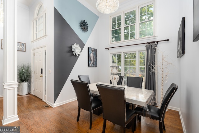 dining space with hardwood / wood-style flooring, a healthy amount of sunlight, and a towering ceiling