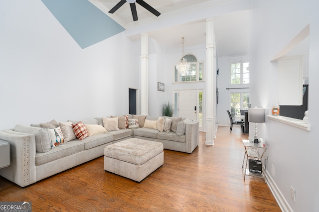 living room with ceiling fan with notable chandelier, a towering ceiling, and wood-type flooring