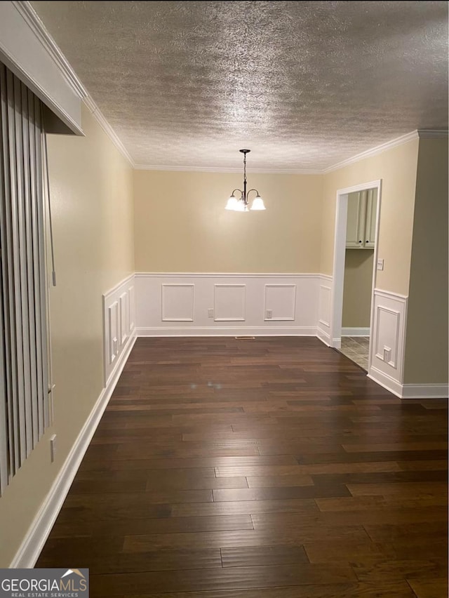 empty room featuring ornamental molding, an inviting chandelier, dark wood-type flooring, and a textured ceiling