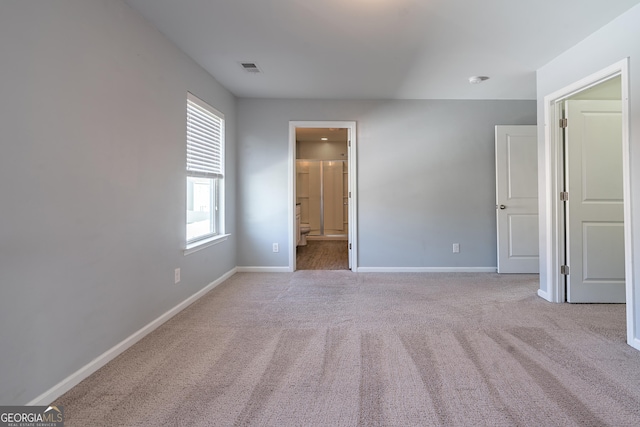 unfurnished bedroom with light carpet and connected bathroom