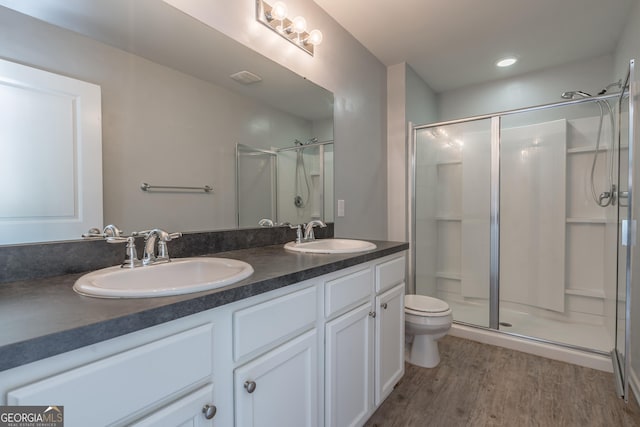 bathroom with hardwood / wood-style flooring, vanity, toilet, and walk in shower