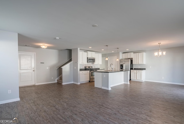 kitchen with a kitchen island with sink, white cabinetry, dark hardwood / wood-style flooring, and stainless steel appliances