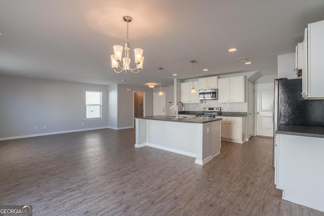 kitchen with dark hardwood / wood-style flooring, an island with sink, decorative light fixtures, white cabinets, and appliances with stainless steel finishes