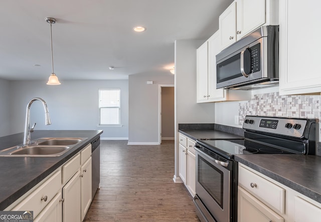 kitchen with dark wood-type flooring, white cabinets, hanging light fixtures, sink, and appliances with stainless steel finishes