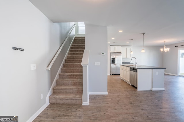 stairs with wood-type flooring, an inviting chandelier, and sink