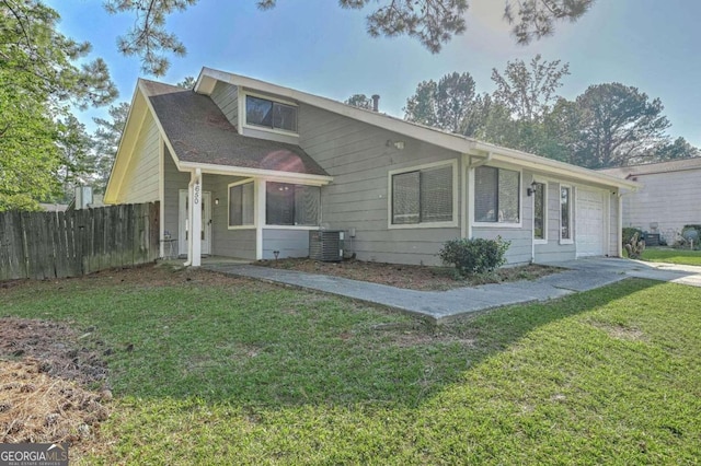 view of front of house with central air condition unit, a front yard, and a garage